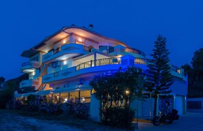 A multi-story residential building with balconies, a motorcycle parked in front, and a well-lit facade. - Zante Sky Suites (Zakynthos)