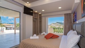 A bedroom with a large bed, a balcony with a view, and a sliding door to an outdoor area. - Zante Sky Suites (Zakynthos)