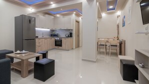 A modern kitchen with a refrigerator, oven, and microwave. There is a dining area with a table and chairs. - Zante Sky Suites (Zakynthos)