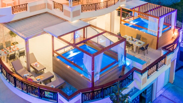 A multi-story building with outdoor pools, a covered patio area, and a dining setup. - Zante Sky Suites (Zakynthos)