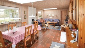 A cozy wooden interior with a dining table set for four, a sofa, and a small kitchen area. - Beautiful home in ørsted with kitchen (Ørsted)