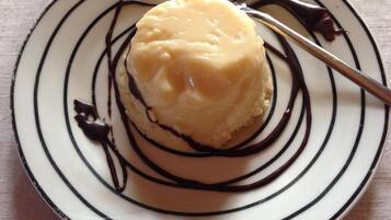 Un dessert présenté dans une assiette, décoré de cercles concentriques, avec une cuillère à proximité.