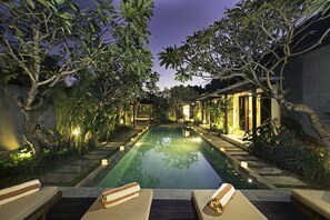 A serene outdoor swimming pool area with lounge chairs and a well-lit pathway. - MD Villa Seminyak by Best Deals Asia Hospitality (Seminyak)