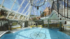Une piscine intérieure dotée d’un toit en verre, de murs en pierre et d’une fontaine centrale.