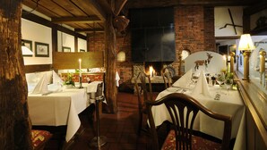 Un restaurant aux murs de briques, aux poutres apparentes et aux tables dressées pour le service.