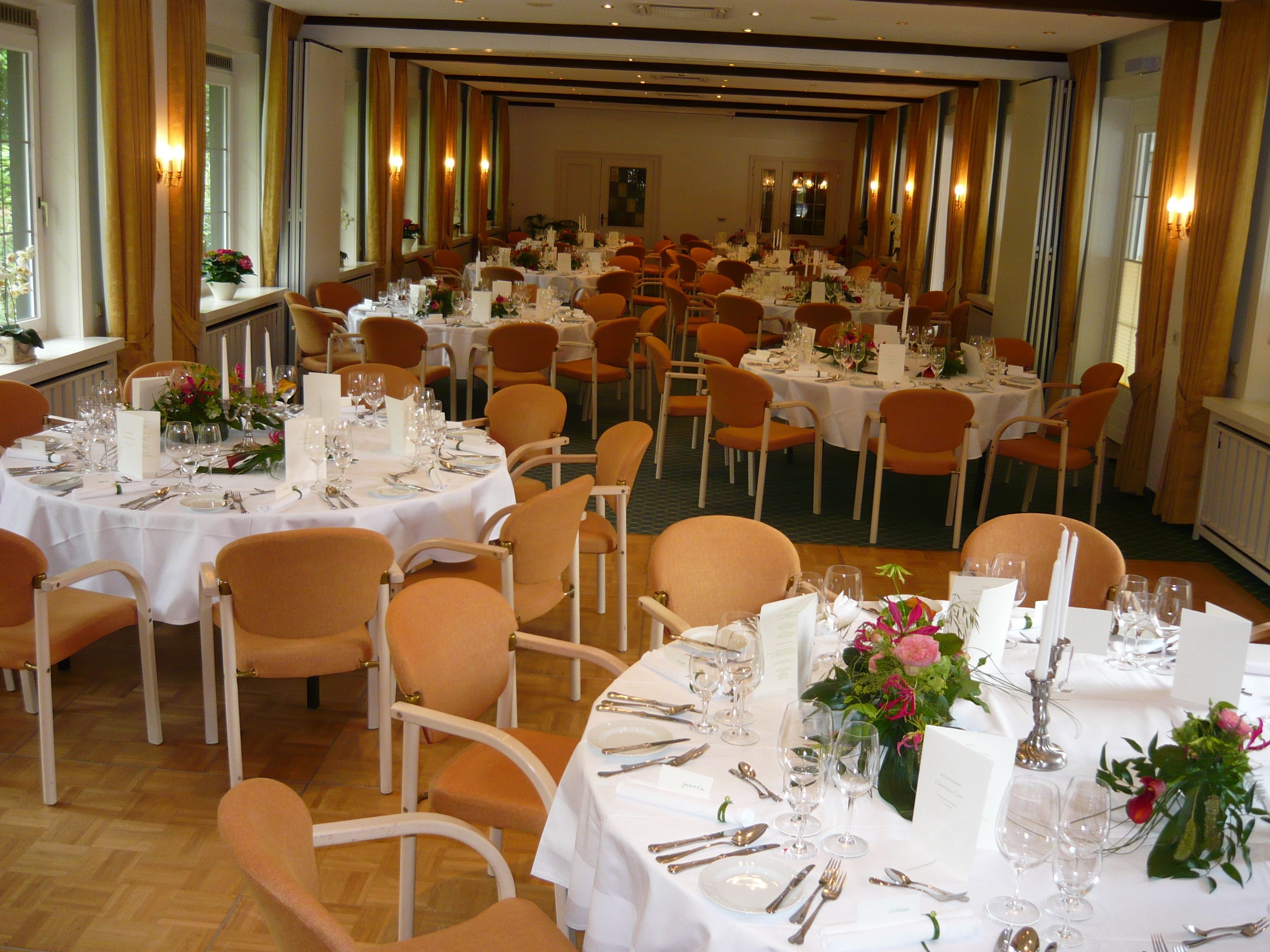 Un salón de banquetes con mesas redondas dispuestas en filas para el servicio de comidas.
