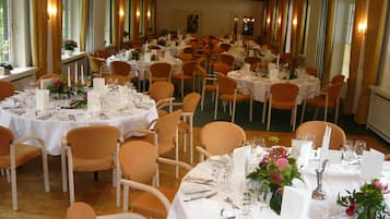 Un salón de banquetes con mesas redondas dispuestas en filas para el servicio de comidas.