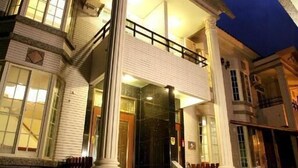 Una casa de dos pisos con un balcón, un porche delantero y una escalera que lleva a la entrada.