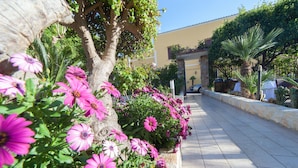 Un sentier bordé de fleurs roses éclatantes et d’un mur de pierre.