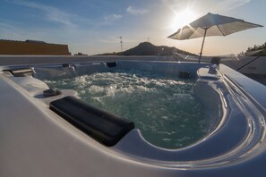 A hot tub on a rooftop with a view of a mountain and the sun setting in the background. - Amaka affittacamere (Custonaci)