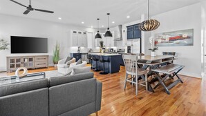 Una cocina moderna con una isla central, armarios blancos e iluminación colgante.