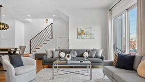 Una sala de estar moderna con un sofá, sillones, una mesa de centro y una escalera.