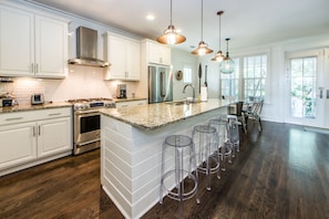 Enjoy cooking in this kitchen with a spacious island, bar stools, and stainless steel appliances.