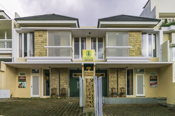 A two-story building with a central entrance, stone facade, and a sign indicating a hotel. - Dhanesvara Holistic Villa (Batu)