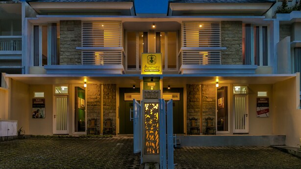 A modern hotel with a symmetrical facade, stone accents, and a central entrance with a decorative gate. - Dhanesvara Holistic Villa (Batu)