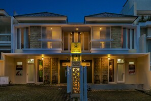 A modern hotel with a symmetrical facade, stone accents, and a central entrance with a decorative gate. - Dhanesvara Holistic Villa (Batu)