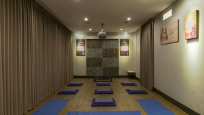 A yoga studio with mats arranged in rows, a wooden floor, and a large wooden panel wall. - Dhanesvara Holistic Villa (Batu)