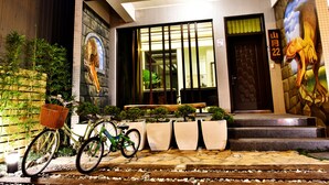 A building entrance with a bicycle parked outside, a mural on the wall, and a sign with the number 94. - shanyue22 (Jiaoxi)
