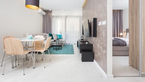 Ein modernes Hotelzimmer mit Essbereich, einer Couch, einem Fernseher und einem Bett.