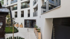 Ein modernes, mehrgeschossiges Gebäude mit Balkonen, einem gepflasterten Innenhof und Holz-Pflanzkästen.