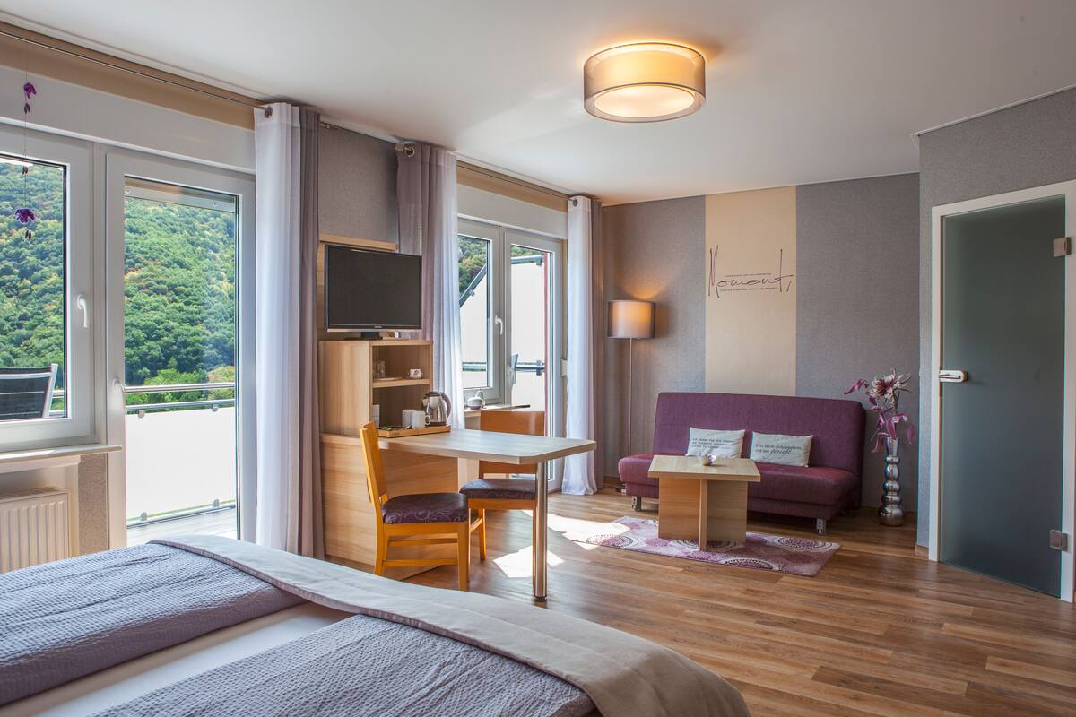 Een moderne hotelkamer met een bed, een bureau, een bank en een televisie.