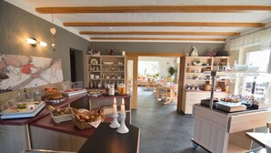 Een ruime keuken met een lange aanrecht, diverse etenswaren en uitzicht op de eethoek.
