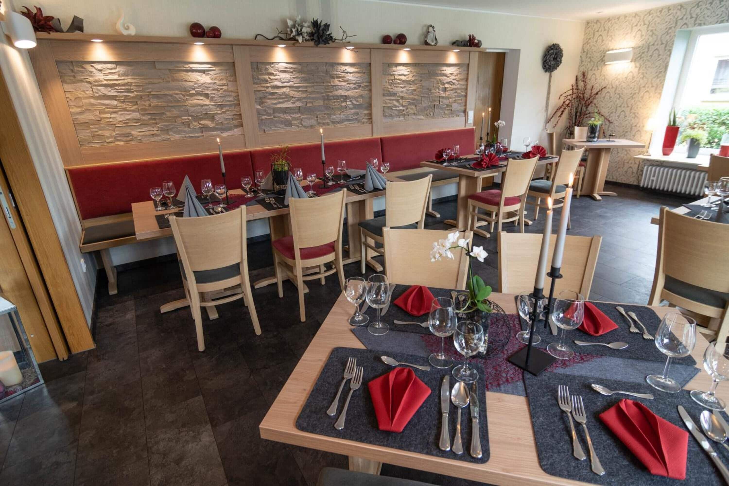 A restaurant with wooden tables and chairs, stone wall decorations, and potted plants.