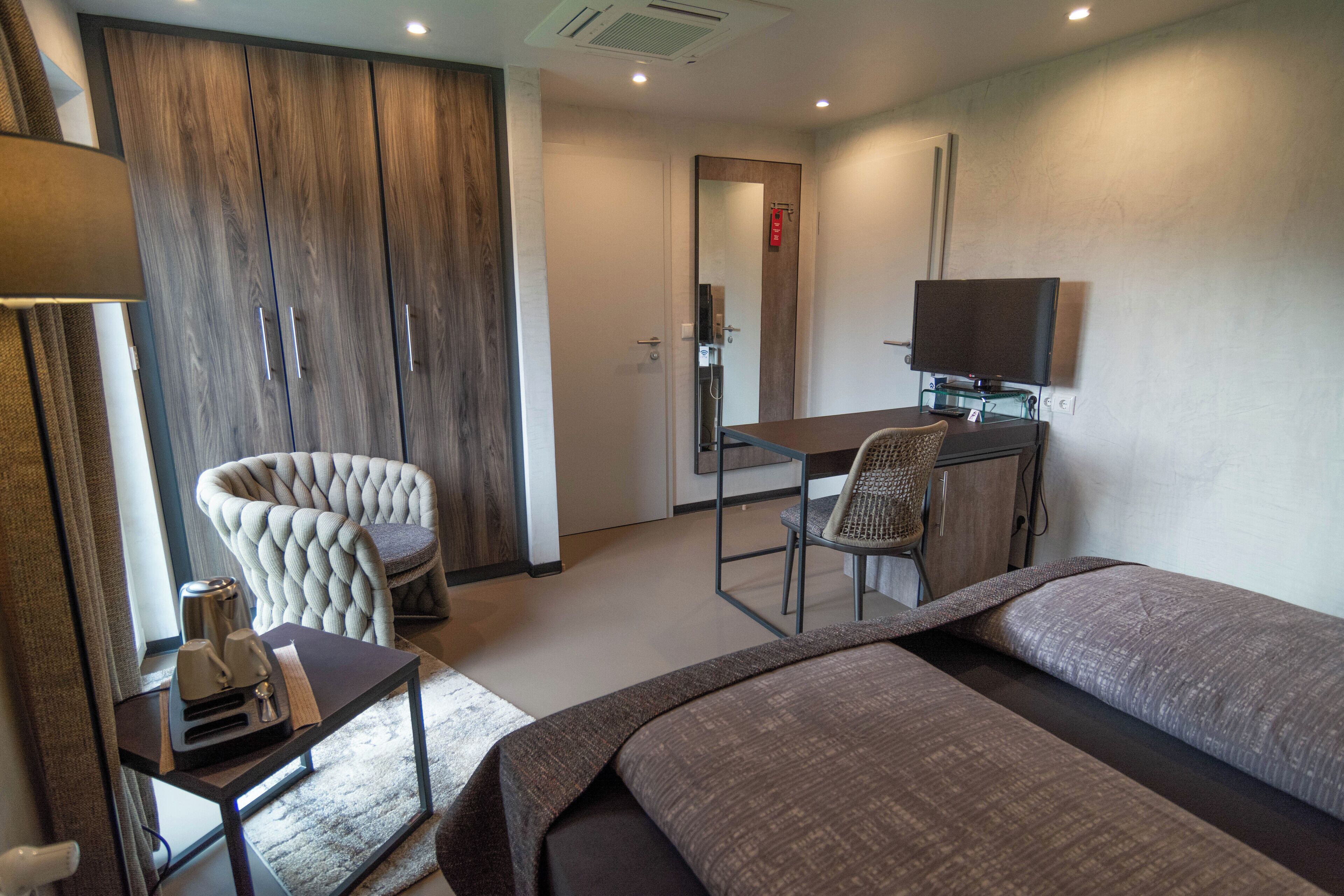 Ein Hotelzimmer mit Bett, Schreibtisch, Stuhl und Kleiderschrank.