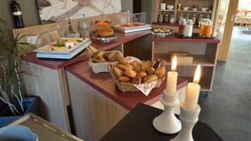 A breakfast buffet with various pastries, a wine bottle, and candles on a table.