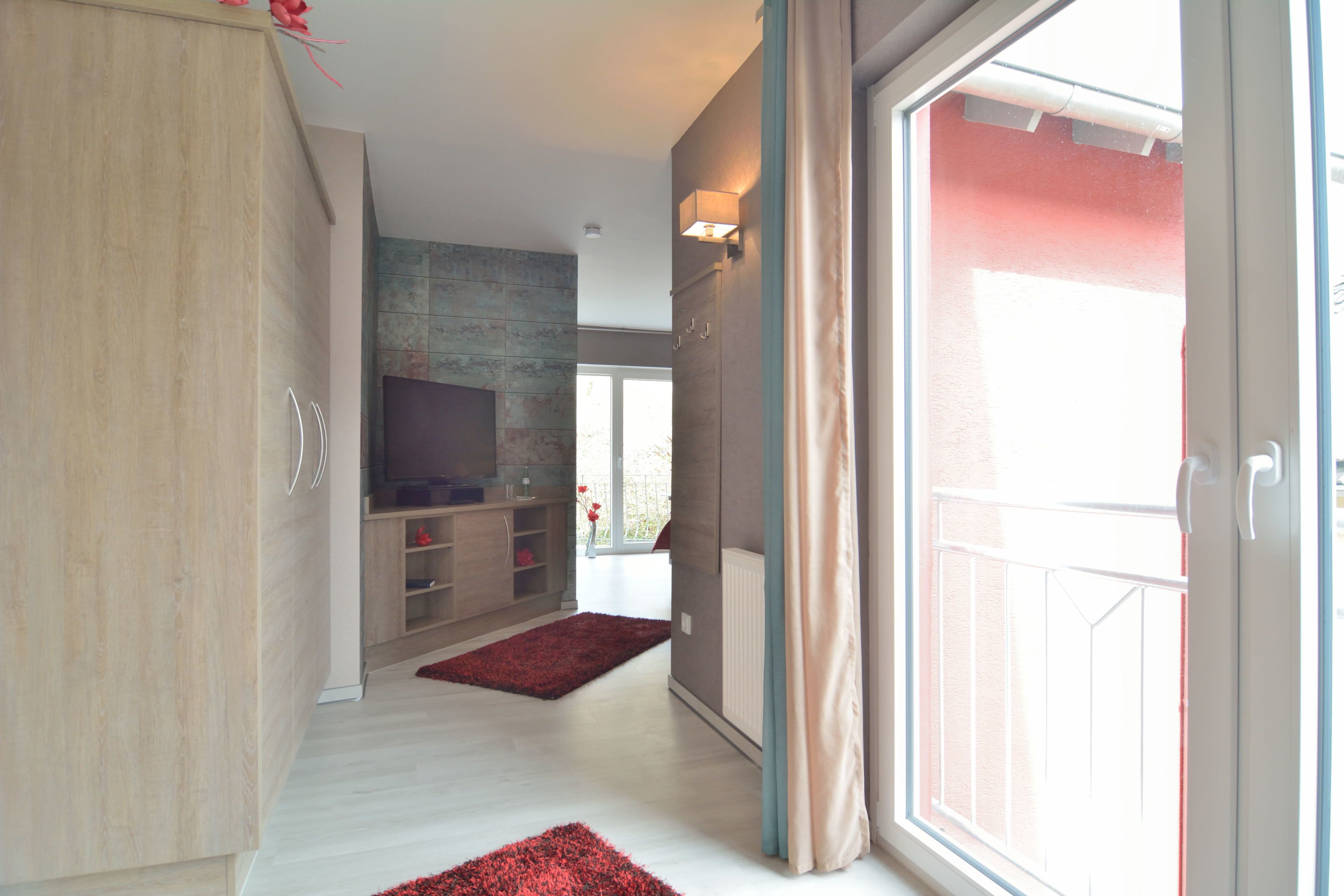 Una sala moderna con un televisor de pantalla plana, armarios de madera y una alfombra roja.