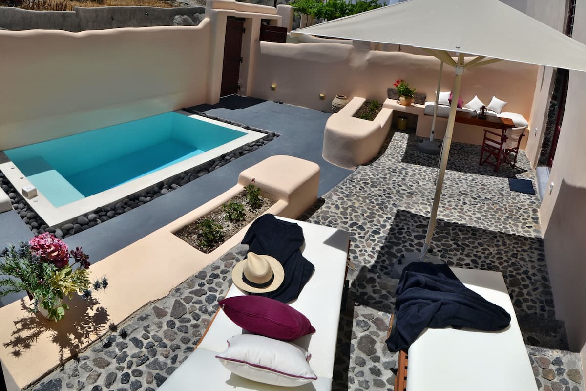 Een zwembadgedeelte met een jacuzzi, ligbedden en een tafel met parasols.