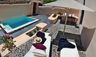 Un área junto a la piscina con hidromasaje, sillones de descanso y una mesa con sombrillas.