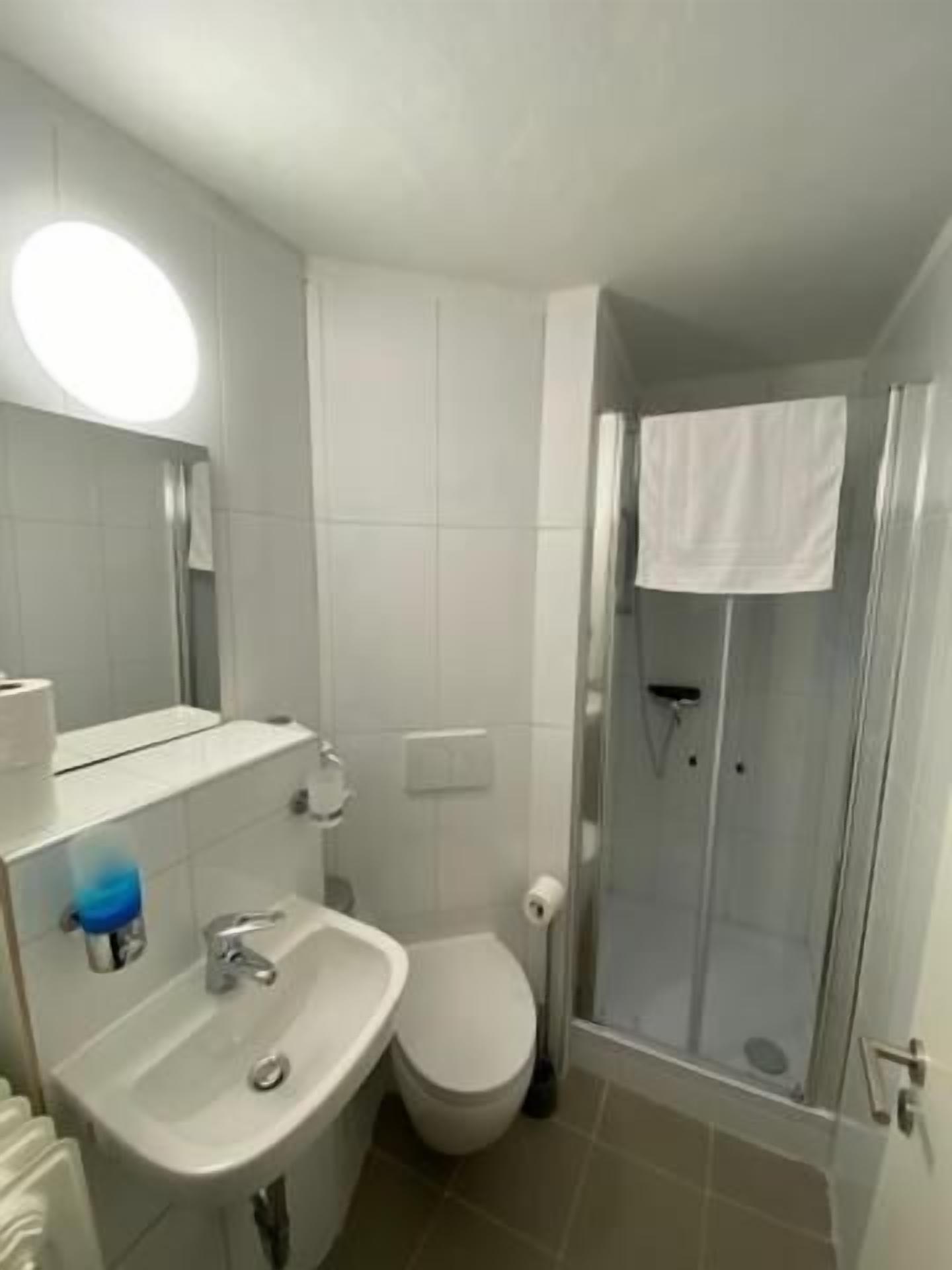 A bathroom with a sink, toilet, and glass-enclosed shower.