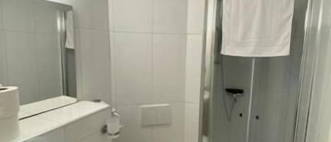 A bathroom with a sink, toilet, and glass-enclosed shower.