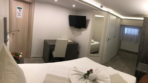 Een hotelkamer met een bed, een bureau, een stoel, een televisie en een badkamer.