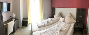 A hotel room with a bed, bedside tables, a TV, and a fan. - Hotel Sophia (Warendorf)