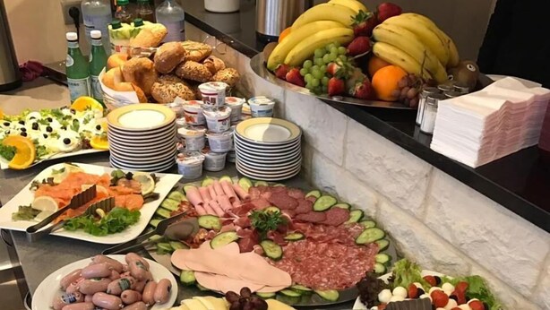 Een buffet met diverse gerechten, waaronder fruit, kazen, vleeswaren en salades.