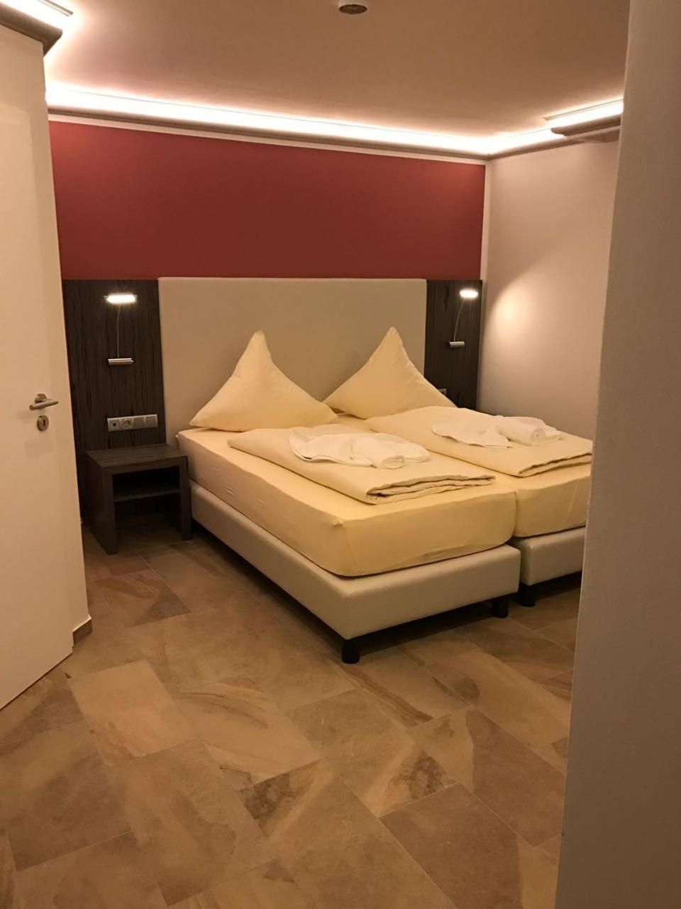 A bedroom with a bed, bedside tables, and a red accent wall.