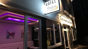 Een hotelgevel met een 'HOTEL Sophia' bord, een restaurant 'Ristorante da Panto' en een kerstboom zichtbaar door het raam.