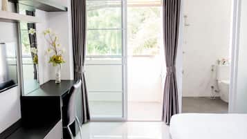 A modern hotel room with a bed, a desk with a chair, a vanity with a mirror, and a bathroom with a toilet and sink.