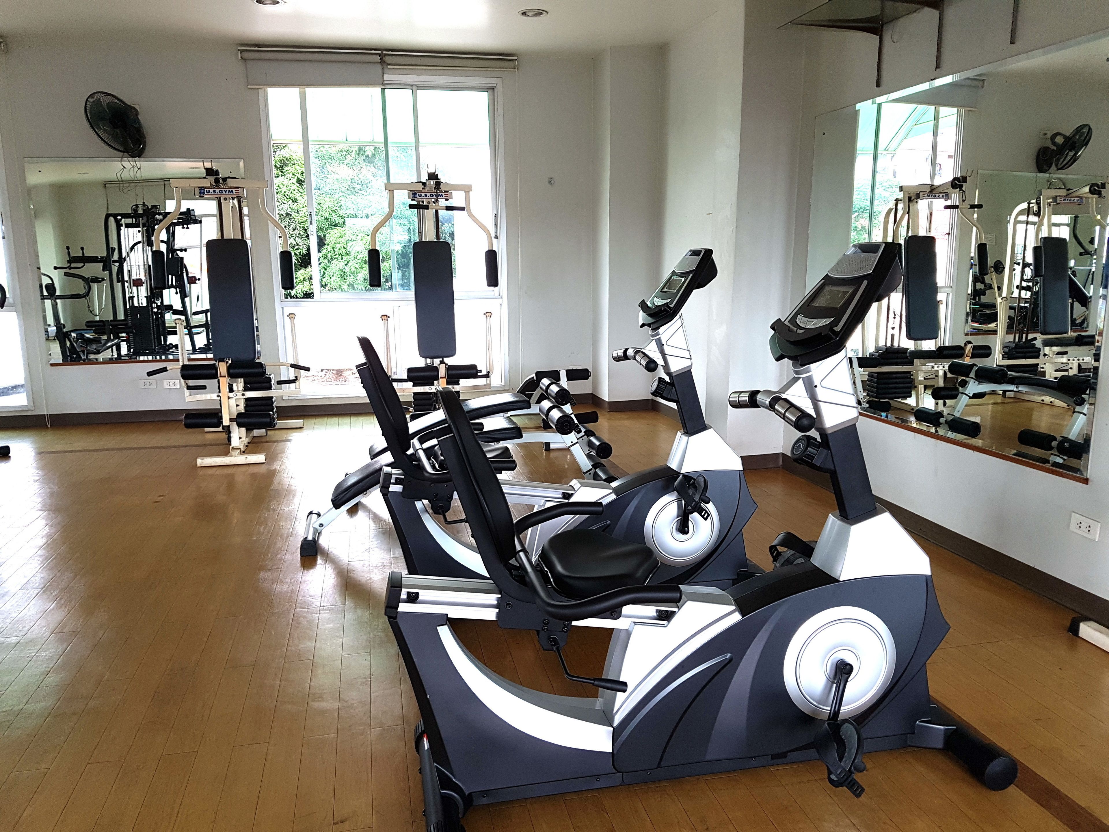 Un gimnasio con equipo de ejercicio, un espejo grande y una ventana que da a zonas verdes.