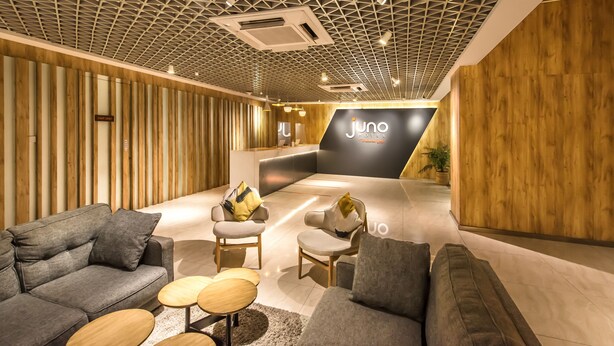 Un hall d’hôtel moderne avec un plafond au design géométrique, un comptoir d’accueil et un mobilier contemporain.