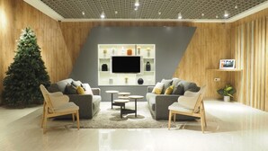 Un salon moderne avec une grande télévision, deux canapés, une table basse et un sapin de Noël.