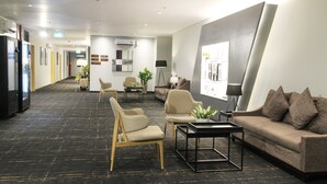 Un hall d’hôtel moderne avec un comptoir d’accueil, un espace salon et une grande fenêtre.