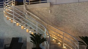 A spiral staircase with illuminated steps leading up to a landing. - Hotel New Belvedere (Mangalia)