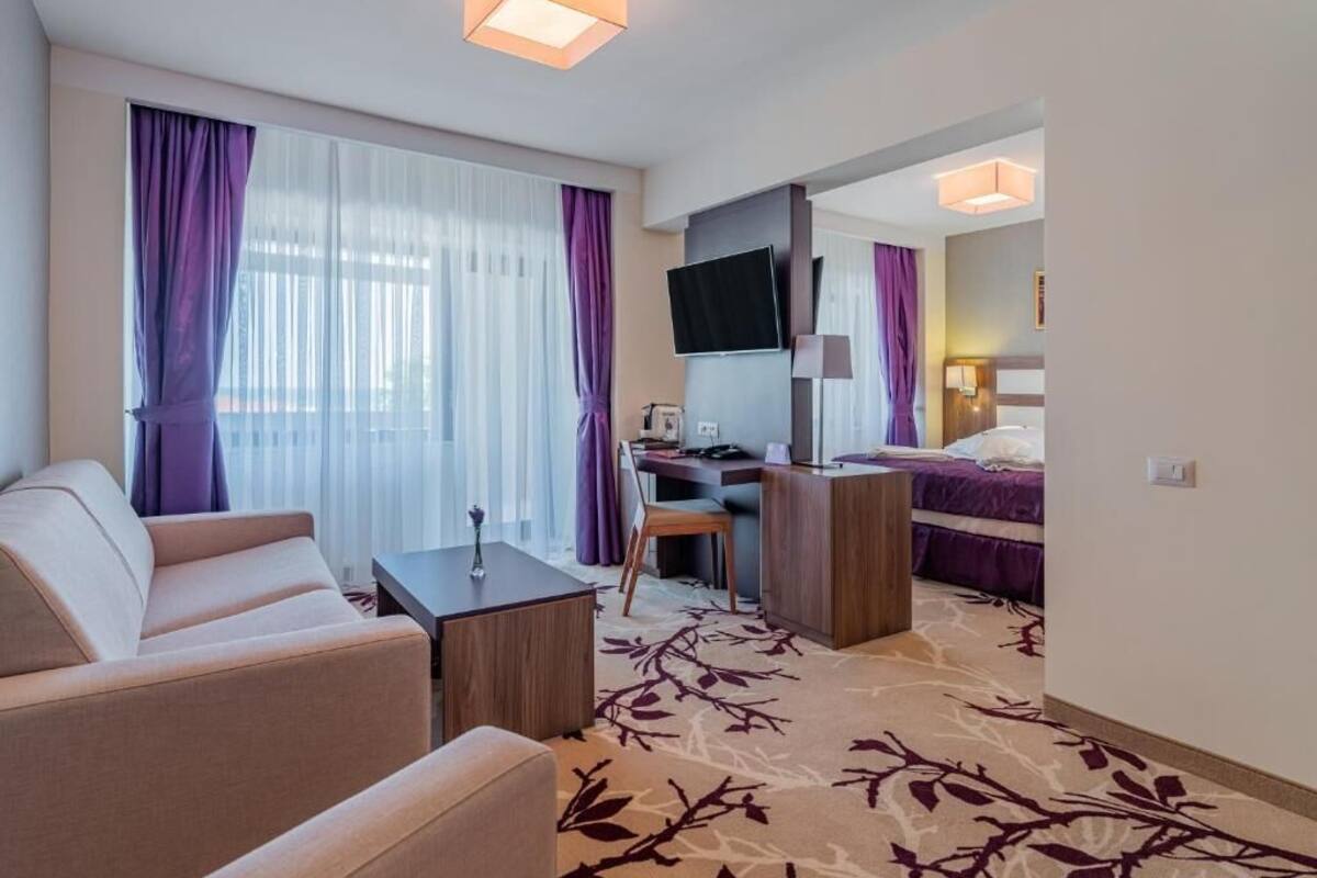 Habitació d'hotel amb sofà, escriptori, llit i televisió.