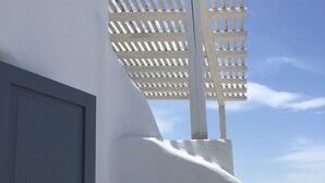 A white building with a door and a window with a white lattice structure above it. - Marquise Residence (Mykonos)