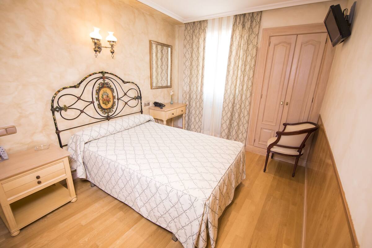 Un dormitorio con cama, mesita de noche, armario y espejo.