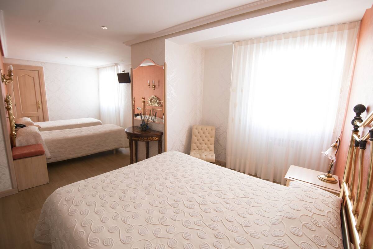 Una habitación de hotel con dos camas, una zona de estar, un escritorio y un espejo.