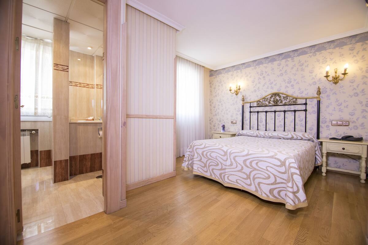Un dormitorio con cama, mesitas de noche, tocador y armario.